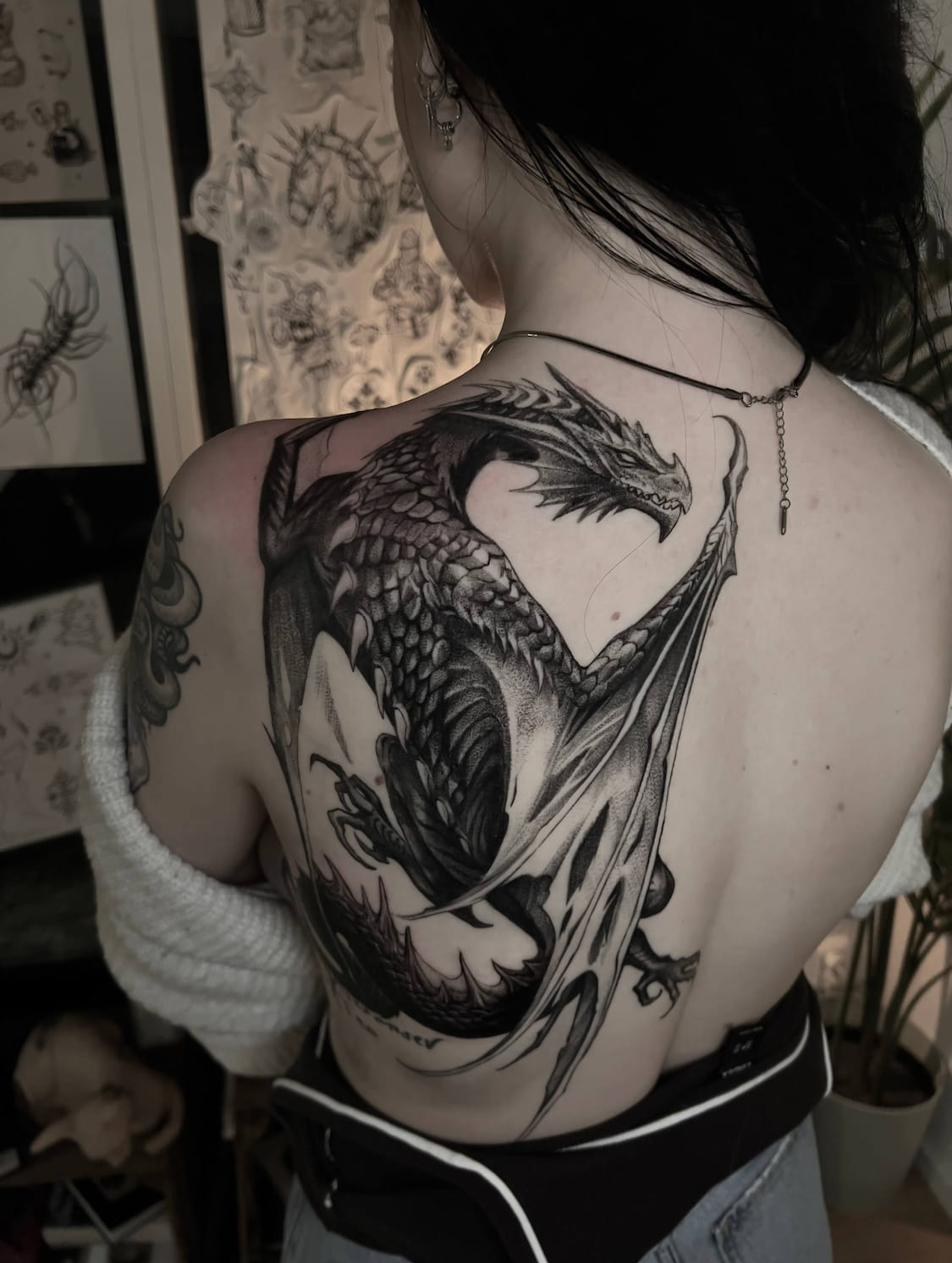 Tatuerare Uppsala — drake i blackwork-realism på rygg och skuldra
