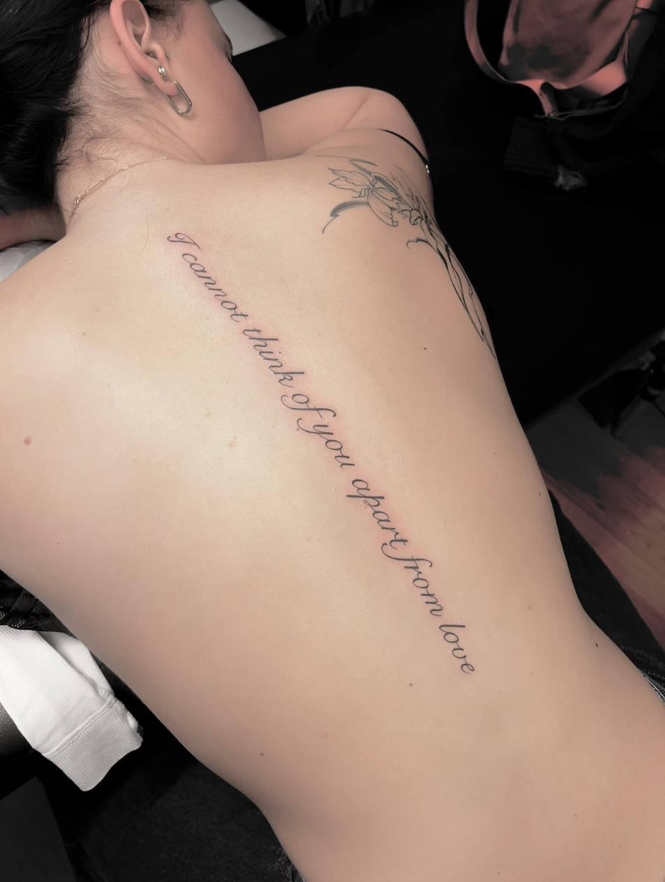 Lettering tatuering Uppsala — citat på rygg, fin skrivstil