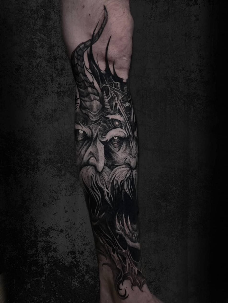 Mörk fantasy tatuerare Uppsala — demonansikte närbild, underben