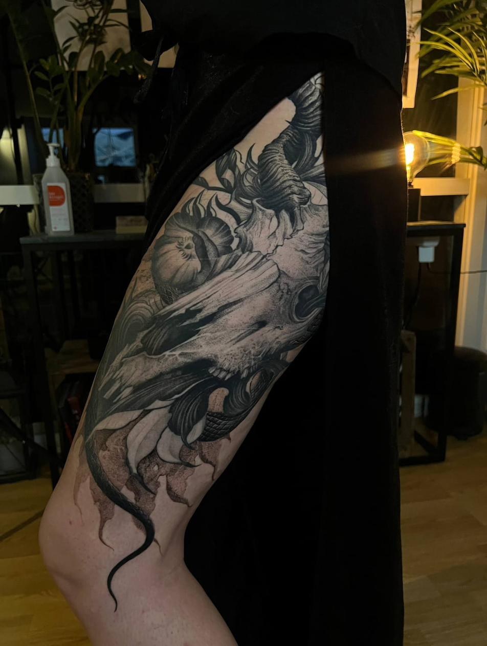 Mörk fantasy tatuerare Uppsala — skalle med orm och blommor, lår